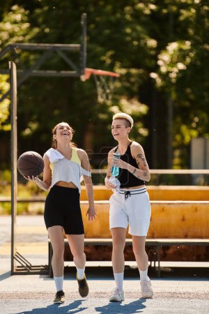 Athletic young women playing basketball together outdoors on a sunny day, showcasing teamwork and friendship.