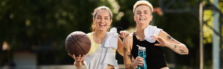 Dwie młode kobiety, przyjaciele i sportowcy, stoją obok siebie na świeżym powietrzu trzymając koszykówkę, gotowe do gry w słoneczny letni dzień.