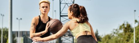 Téléchargez les photos : Deux jeunes femmes athlétiques profitent d'un jeu de basket-ball en plein air par une journée ensoleillée. - en image libre de droit
