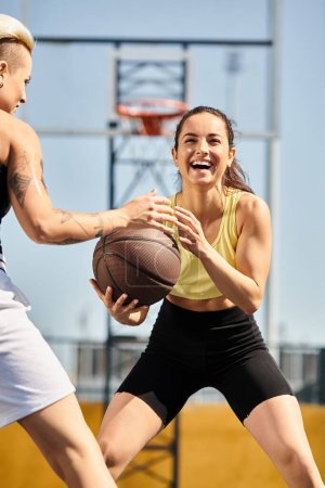 Zwei junge, athletische Frauen stehen zusammen, eine hält einen Basketball in der Hand, bereit, an einem sonnigen Sommertag draußen Basketball zu spielen.