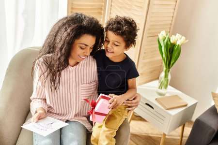 joyful beautiful african american woman receiving postcard and gift from her son, Mothers day