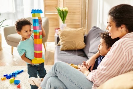 little african american boy showing cube tower to his brother and mother while playing at home