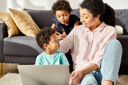 Téléchargez les photos : Joyeuse jolie mère afro-américaine regardant ses deux fils avec amour en regardant des films - en image libre de droit