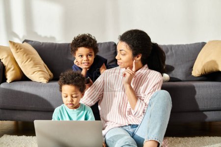 Téléchargez les photos : Attrayant joyeux afro-américain mère regardant ses fils avec amour tout en regardant des films - en image libre de droit