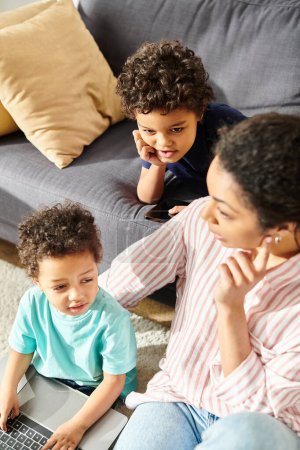gut aussehende afrikanisch-amerikanische Mutter mit ihren entzückenden kleinen Söhnen im Wohnzimmer