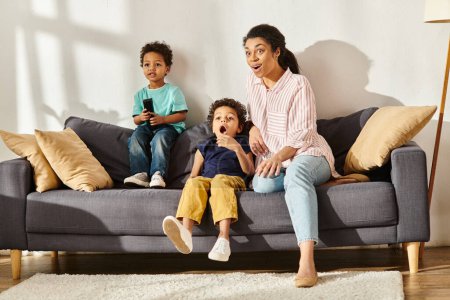 shocked african american mother watching interesting movies with her surprised little sons