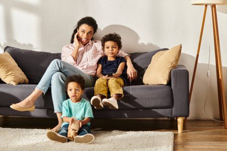 fröhliche afrikanisch-amerikanische Mutter verbringt Zeit mit ihren Söhnen vor dem Fernseher im heimischen Wohnzimmer
