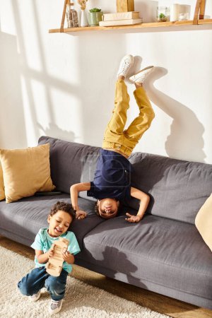 alegre lindo africano americano hermanos en cómodo homewear divertirse juntos en sala de estar en sofá