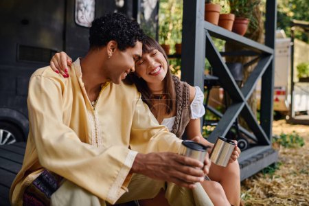 Téléchargez les photos : Un homme et une femme, un couple interracial, assis ensemble sur le sol, profitant d'une escapade romantique dans un cadre naturel. - en image libre de droit