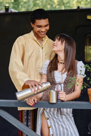 Téléchargez les photos : Un couple interracial profitant d'un moment romantique ensemble tout en se tenant côte à côte dans un cadre naturel. - en image libre de droit