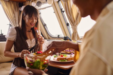 Un homme et une femme profitent d'un repas ensemble sur un bateau tout en admirant la vue panoramique autour d'eux lors d'une escapade romantique.