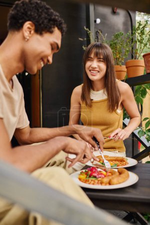 Una pareja interracial disfruta de una comida acogedora en una caravana, saboreando cada bocado de deliciosa comida juntos.
