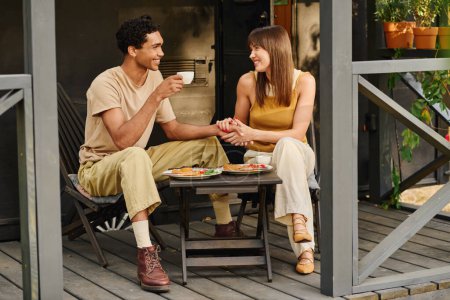 A man and a woman sit on a porch, enjoying a delicious meal together.