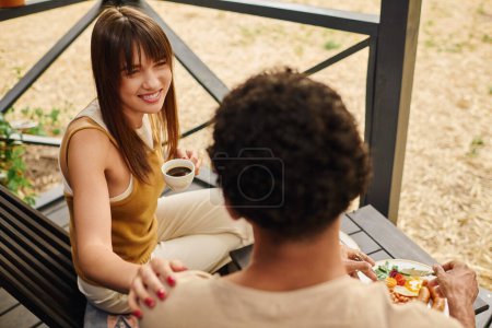 Téléchargez les photos : Un couple interracial est assis ensemble sur un banc, profitant d'un moment serein de convivialité. - en image libre de droit