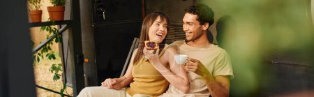 Téléchargez les photos : Un homme et une femme se détendre sur un porche, se prélasser dans l'atmosphère paisible comme ils partagent un moment calme ensemble. - en image libre de droit