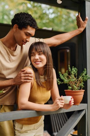 A man and woman stand together on a balcony, enjoying a romantic moment.