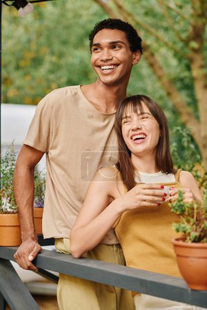 Ein Mann und eine Frau unterschiedlicher Rassen stehen während eines romantischen Kurzurlaubs zusammen an einem Wohnmobil.