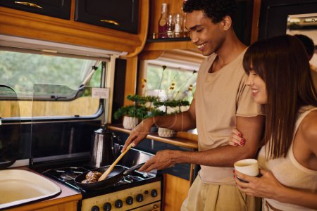 An interracial couple cooking in their camper, preparing a meal together in the cozy confines of their mobile kitchen.