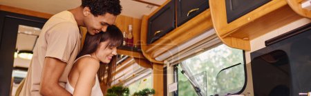 Photo for An interracial couple sitting side by side, engrossed in cooking inside of van - Royalty Free Image