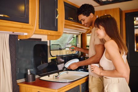 Foto de Un hombre y una mujer de pie en una cocina junto a un fregadero, compartiendo un momento pacífico de unión. - Imagen libre de derechos