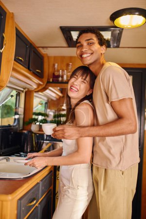 Un hombre y una mujer de pie en una acogedora cocina, preparando una comida juntos, rodeados de ollas y sartenes.