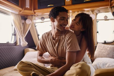 Ein Mann und eine Frau sitzen eng auf einem Bett und teilen intime Momente in einem gemütlichen Rahmen.