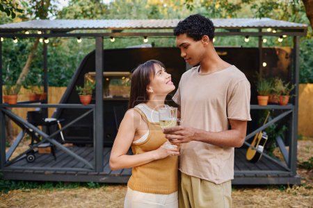 Un homme et une femme, un couple interracial, se tiennent ensemble, embrassant, sur fond de camping-car.