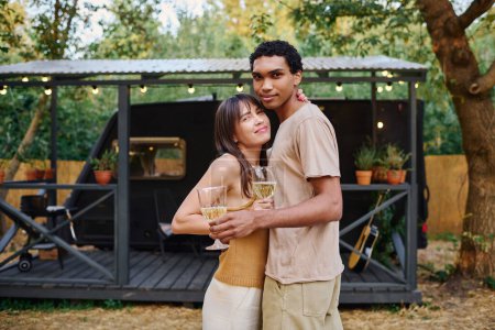 Foto de Un hombre y una mujer, una pareja interracial, se paran uno al lado del otro, embarcándose en una escapada romántica en una caravana. - Imagen libre de derechos