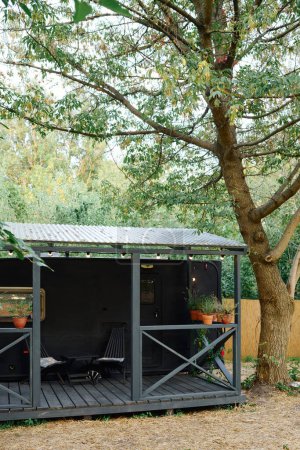 Un charmant petit hangar se trouve à côté d'un arbre majestueux, créant une scène pittoresque et sereine dans la nature.