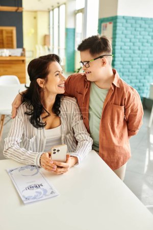 attractive happy mother in casual clothes with her inclusive son with Down syndrome holding menu