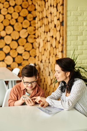 Photo for Good looking mother in casual clothes with inclusive son with Down syndrome looking at menu on phone - Royalty Free Image
