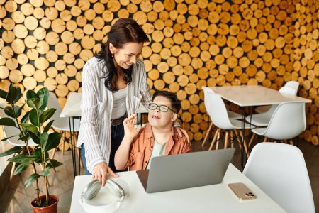 adorable inclusive boy with Down syndrome spending time with his joyful mother in front of laptop
