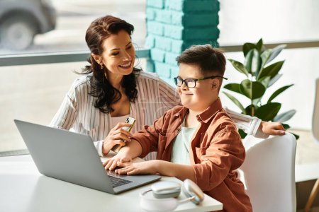 Photo for Adorable inclusive boy with Down syndrome spending time with his joyful mother in front of laptop - Royalty Free Image