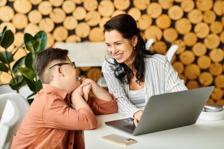 adorable inclusive boy with Down syndrome spending time with his jolly mother in front of laptop