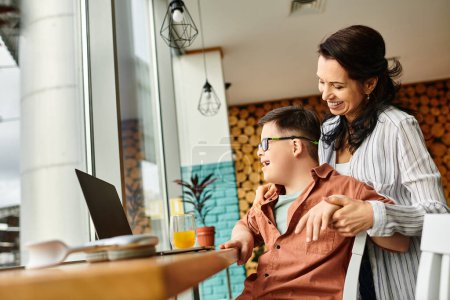 Photo for Joyous mother spending time with her inclusive son with Down syndrome in front of laptop in cafe - Royalty Free Image