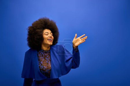 Trendy African American woman with curly hairdosmiling and waving.