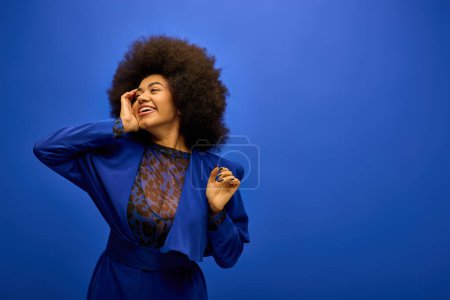 Stylish African American woman with curly hairdohair poses for a trendy photo on a vibrant backdrop.