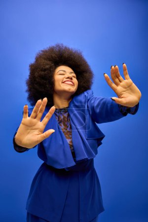 A stylish African American woman with curly hairdomakes a striking hand gesture.