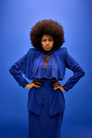 Stylish woman with curly hairdohair strikes a pose in front of vibrant blue backdrop.