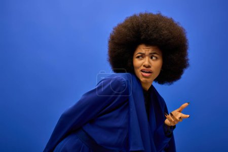 A stylish African American woman in trendy attire with curly hairdois making a funny face.