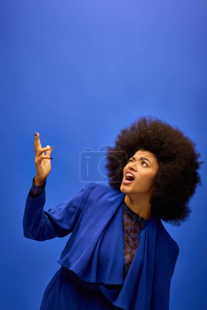 Stylish African American woman with curly hairdomakes a funny face on vibrant backdrop.