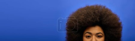 Mujer afroamericana con estilo en traje de moda haciendo una cara divertida con su pelo afro.