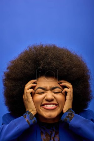 Una elegante mujer afroamericana con el pelo rizado sosteniendo sus manos en su cara en un momento de reflexión.
