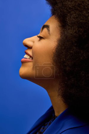 A stylish African American woman with a voluminous afro posing against a vibrant backdrop.