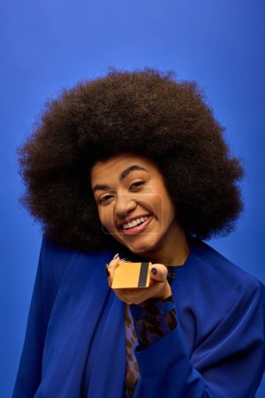 Stylish African American woman with curly hairdohair holding credit card.