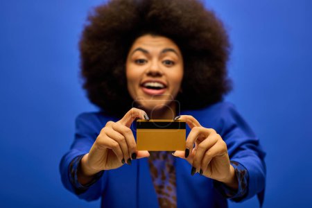 Stilvolle Afroamerikanerin mit Kreditkarte vor lebendiger Kulisse.