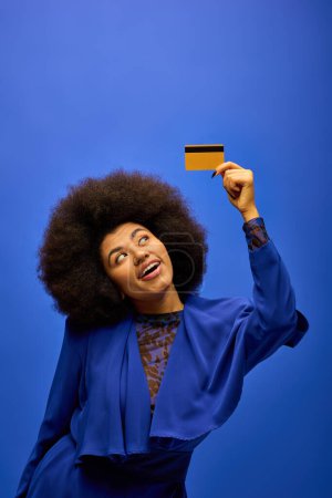 Elegante mujer afroamericana con el pelo rizado sosteniendo una tarjeta de crédito.
