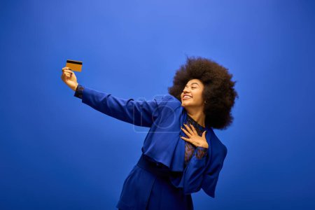 Foto de Mujer afroamericana con estilo en traje de moda sostiene una tarjeta con un vibrante telón de fondo. - Imagen libre de derechos