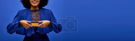 Téléchargez les photos : A stylish African American woman in trendy attire holding a small yellow object in her hands. - en image libre de droit
