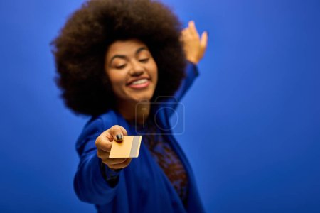Téléchargez les photos : Femme afro-américaine élégante en tenue tendance tenant une carte de crédit. - en image libre de droit